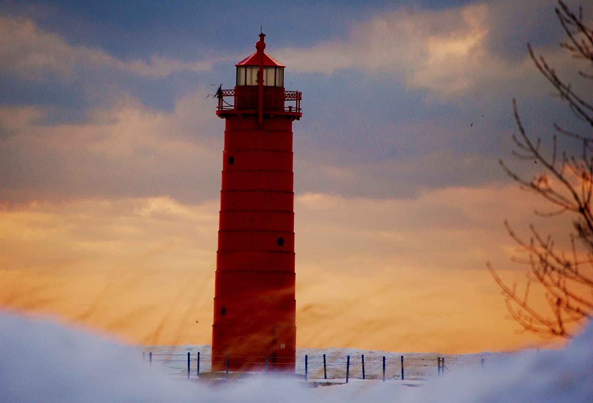 The red Muskegon South Pierhead Light on the Pere Marquette pier, glowing at golden hour